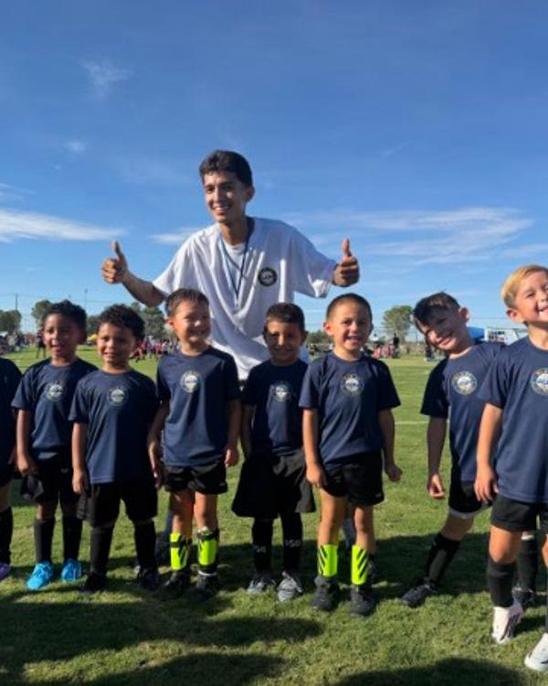 The U5 team lined up with their coach, thumbs up