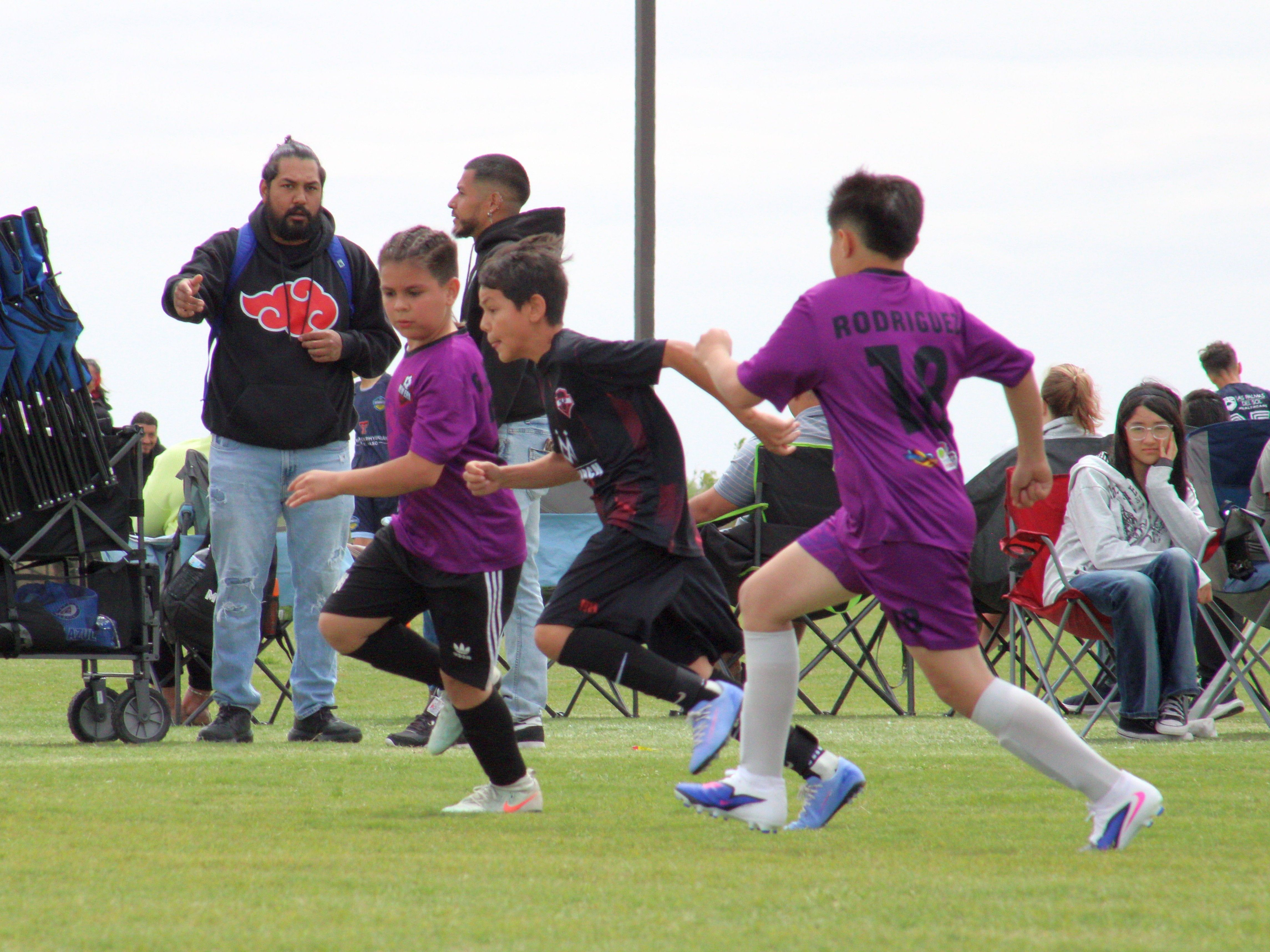 Players contesting the ball in front of the families on the sideline