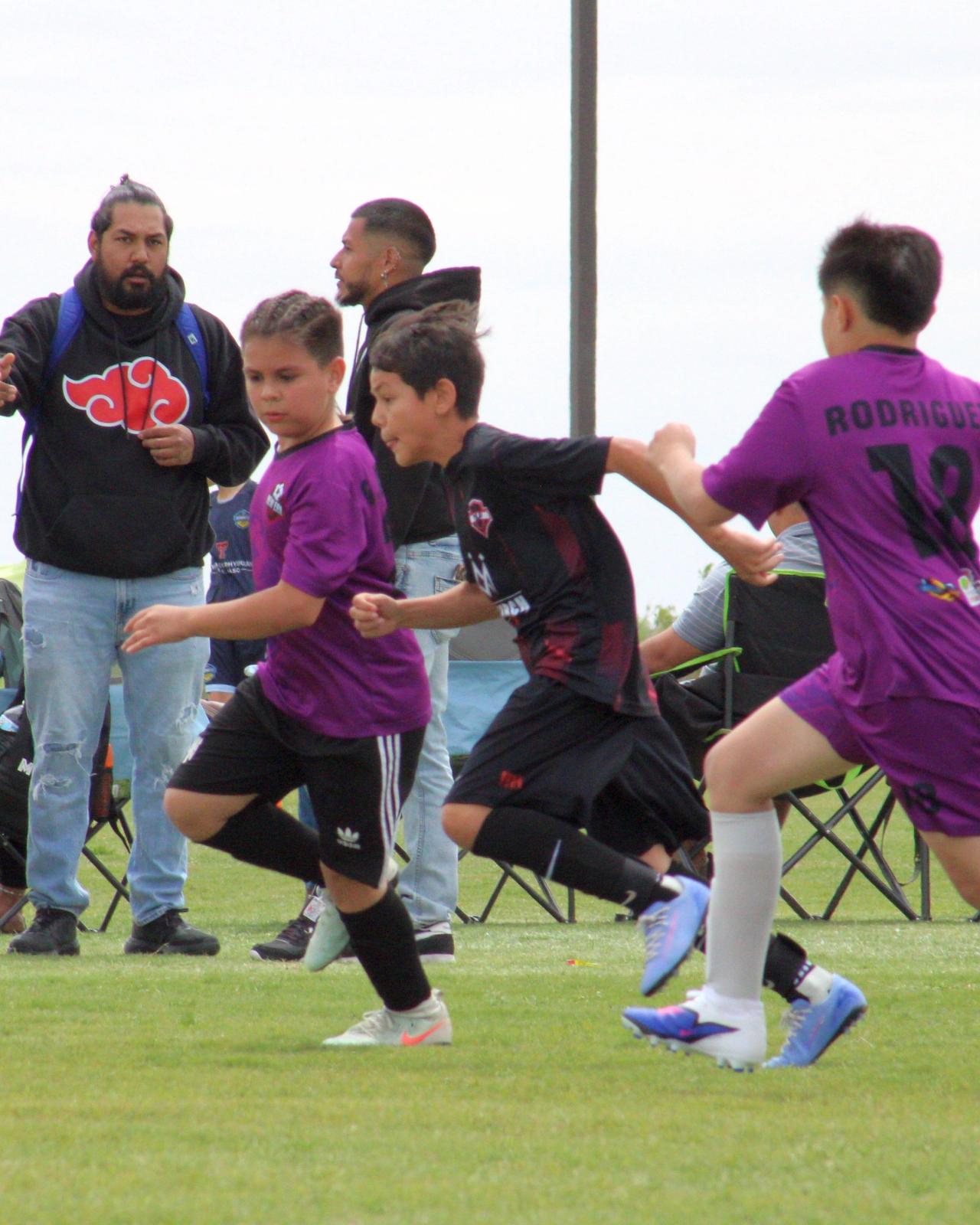 Players contesting the ball in front of the families on the sideline