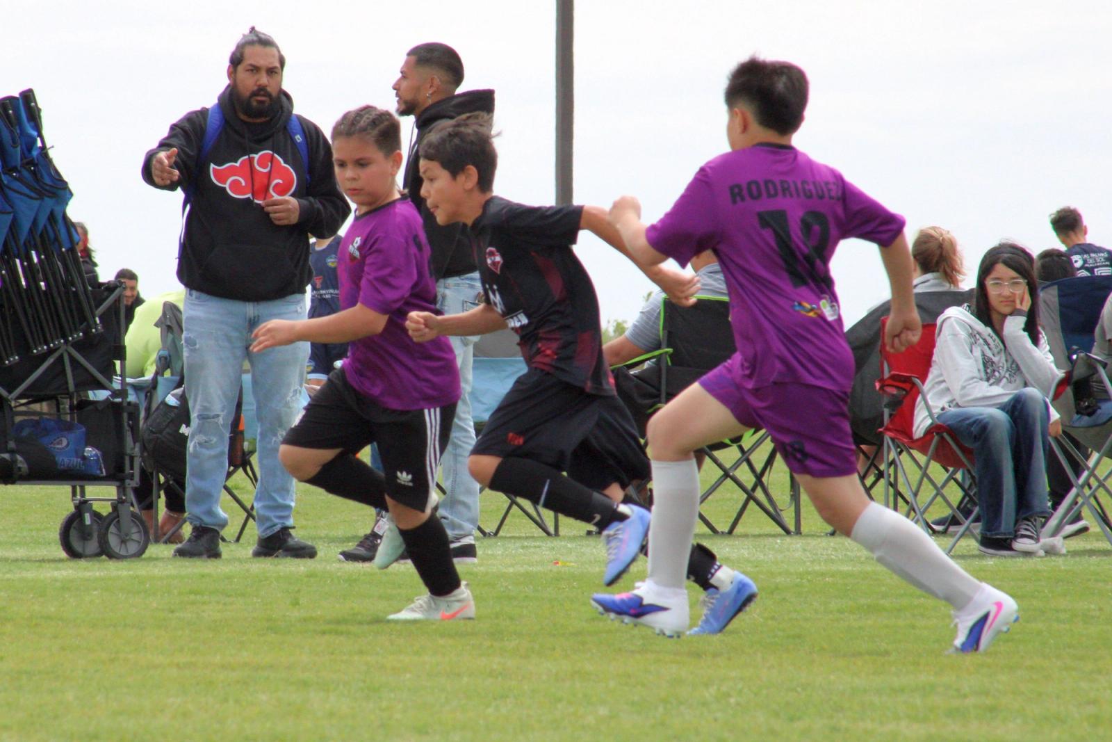 Players contesting the ball in front of the families on the sideline