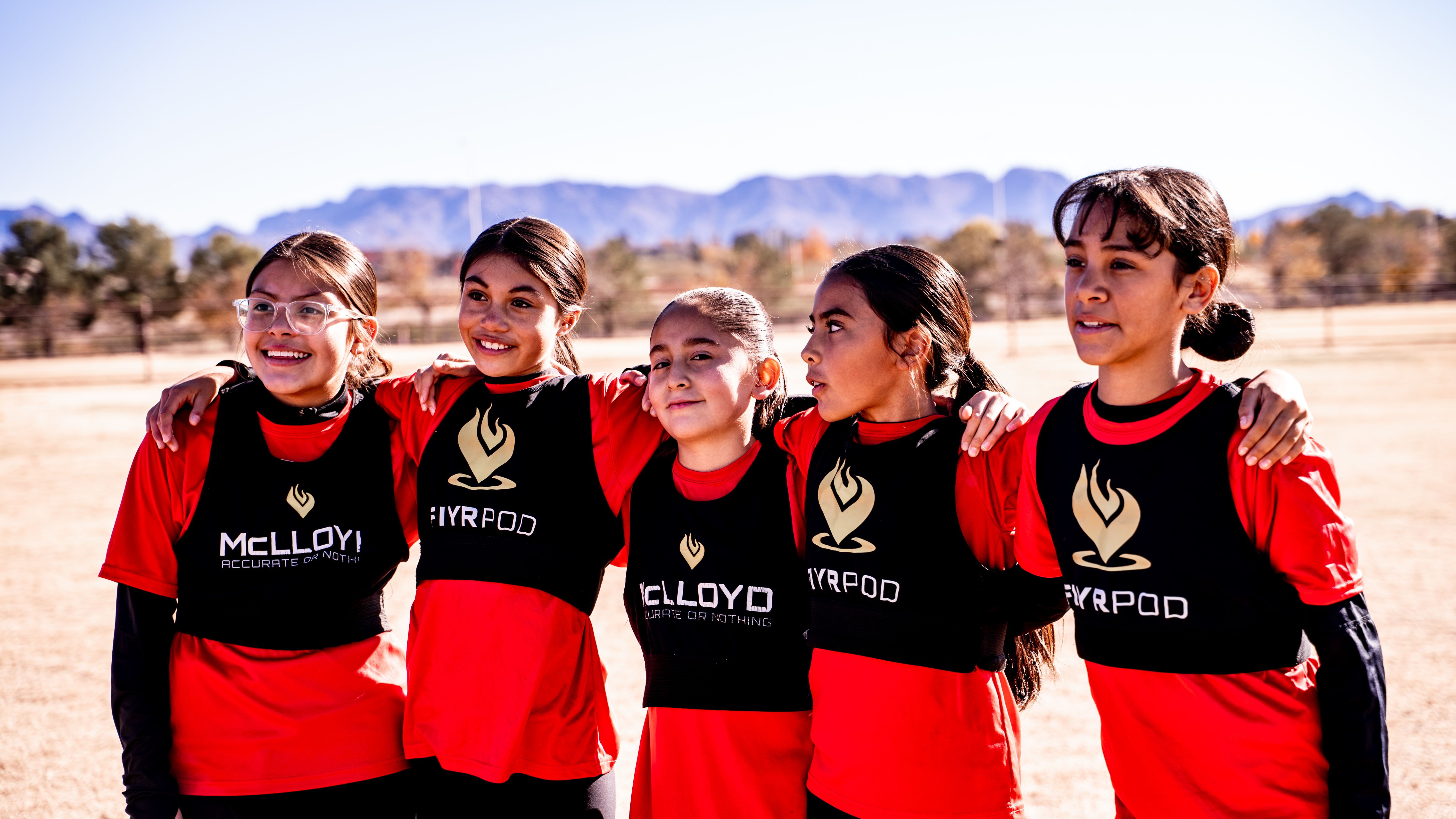 Girls U14 players arm in arm with the Organ Mountains behind them