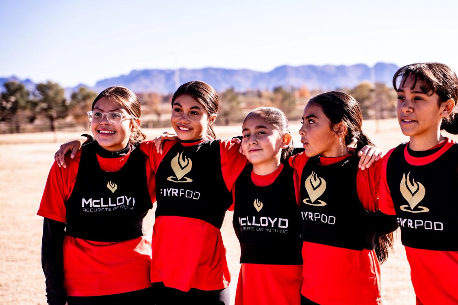 Girls U14 players arm in arm with the Organ Mountains behind them