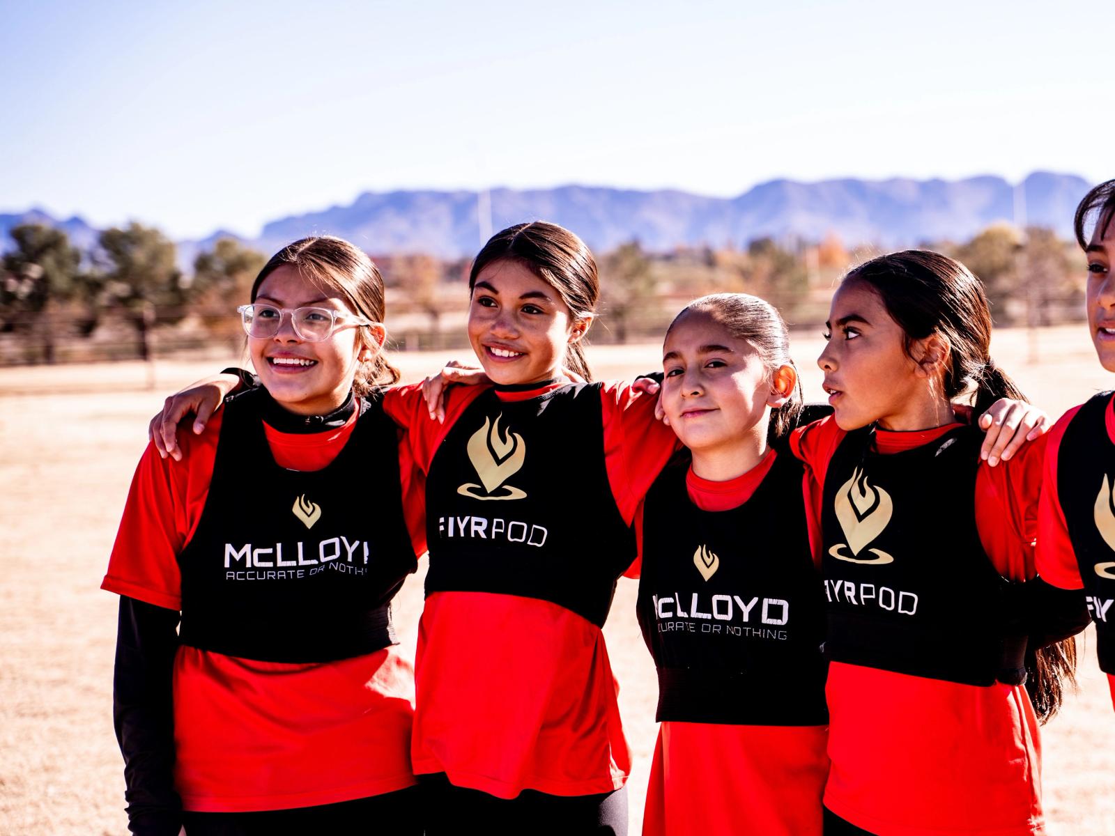 Girls U14 players arm in arm with the Organ Mountains behind them
