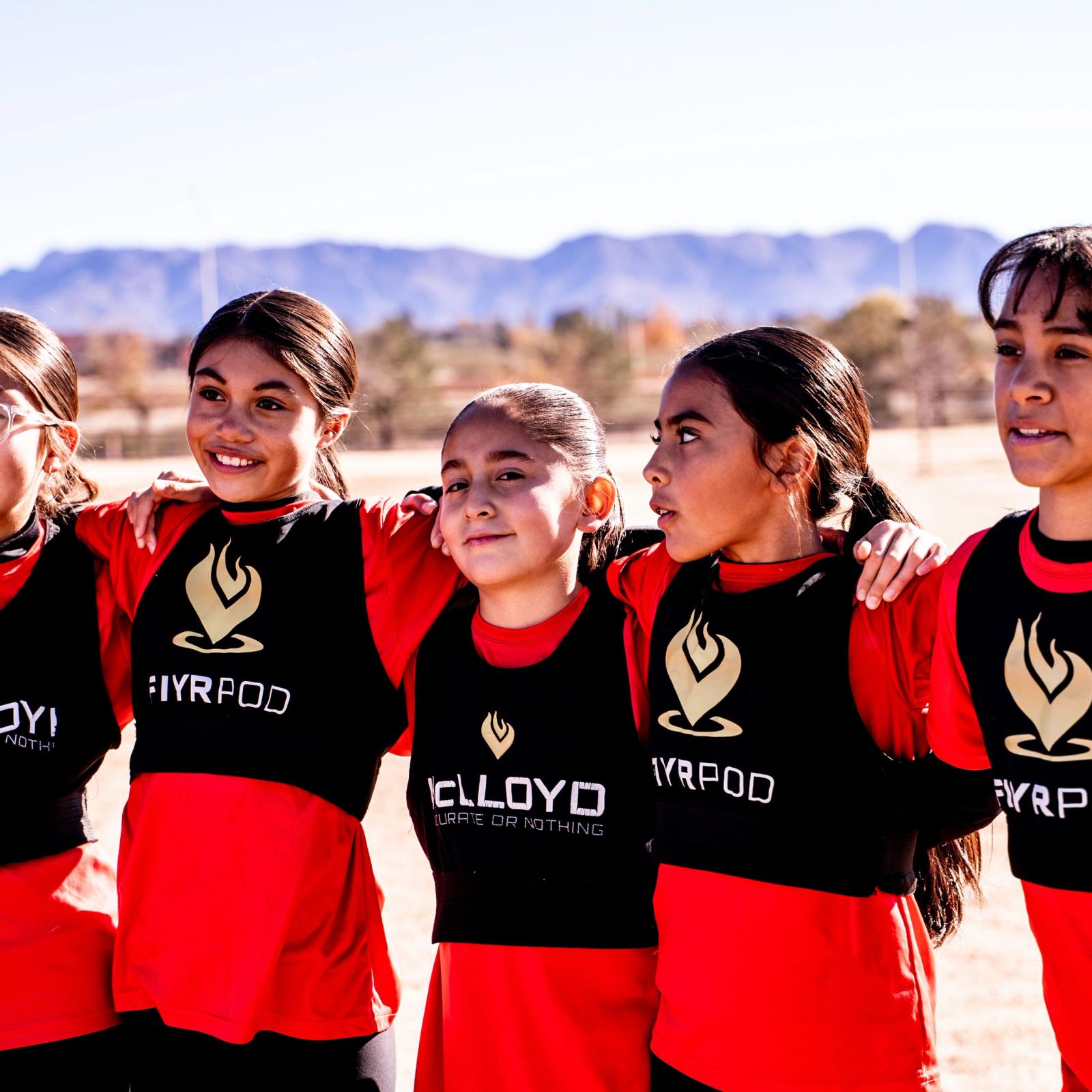 Girls U14 players arm in arm with the Organ Mountains behind them