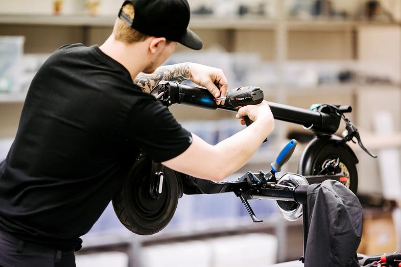 un homme réparant une trottinette Augment