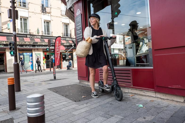 Une femme avec un scooter électrique Augment dans le centre ville.