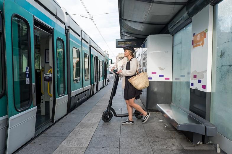 A woman stepping in to the train with an Augment e-scooter