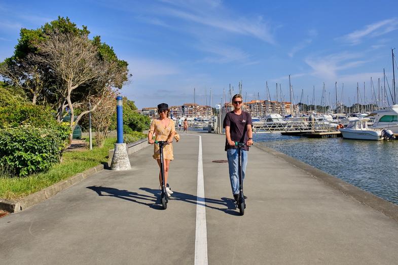 A man and a woman riding Augment e-scooters on a promenade