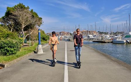En mand og en kvinde kører på Augment e-scootere på en promenade