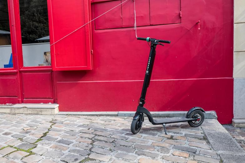 Augmentation de la vue latérale de l'e-scooter dans la rue devant le mur rouge
