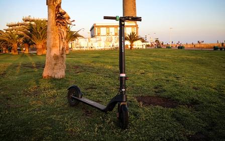 Vue de face d'un Augment e-scooter sur une pelouse au coucher du soleil