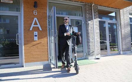 Un uomo che esce da casa sua con un e-scooter Augment