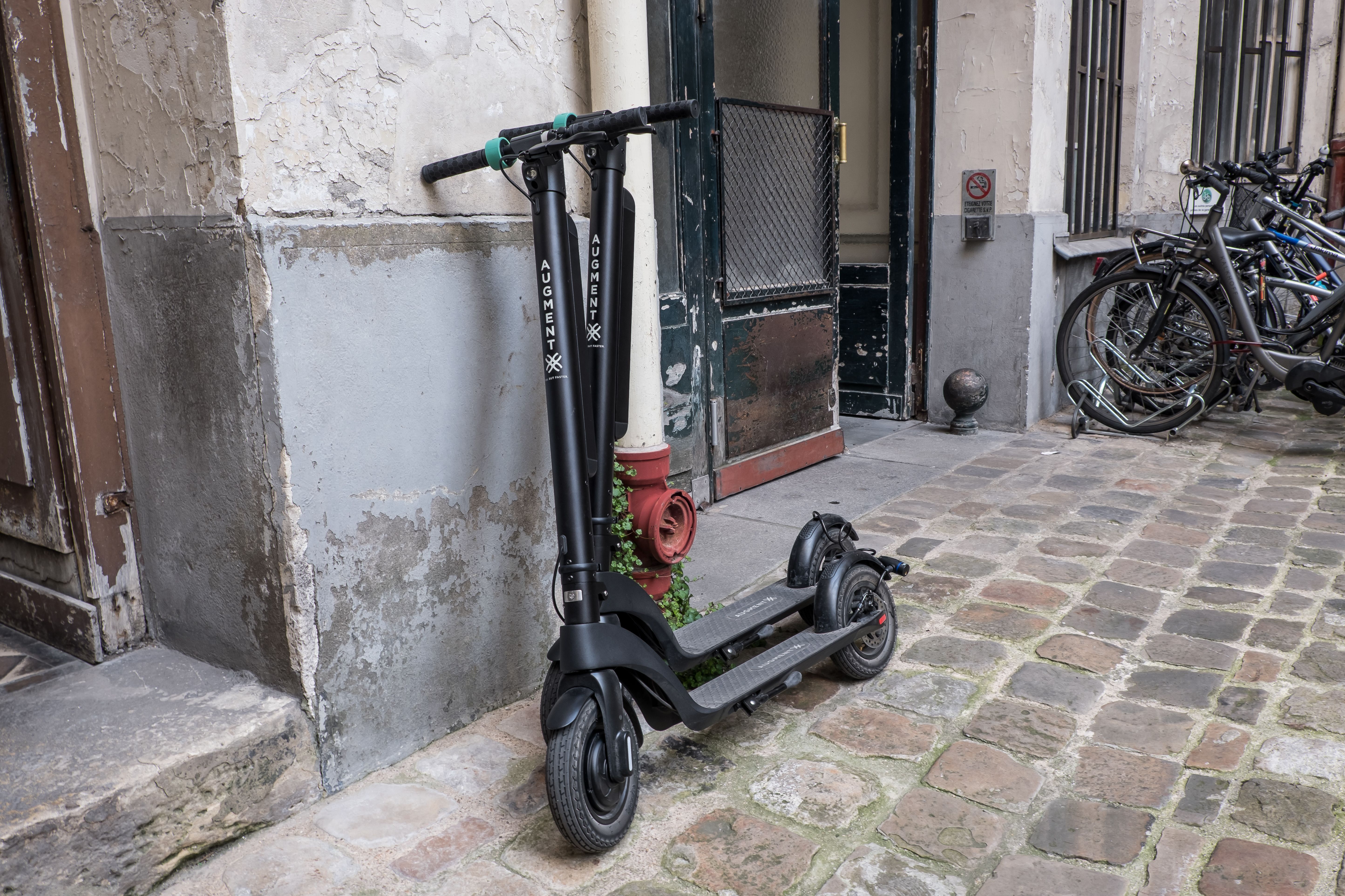 Deux e-scooters Augment appuyés sur un mur dans la rue de la vieille ville