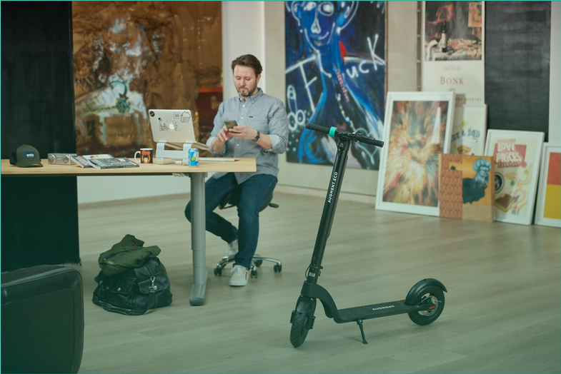 Un homme au bureau avec un e-scooter Augment