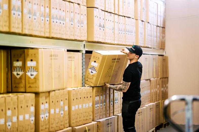 An Augment employee taking an e-scooter postal package from the shelf