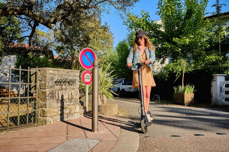 Une femme conduit un scooter électrique Augment dans un quartier.