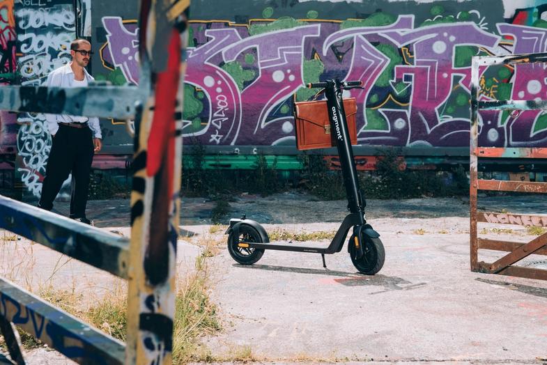 Augment e-scooter side view in front of wooden wall