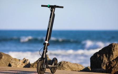 Frontalbillede af en Augment e-scooter med havet i baggrunden