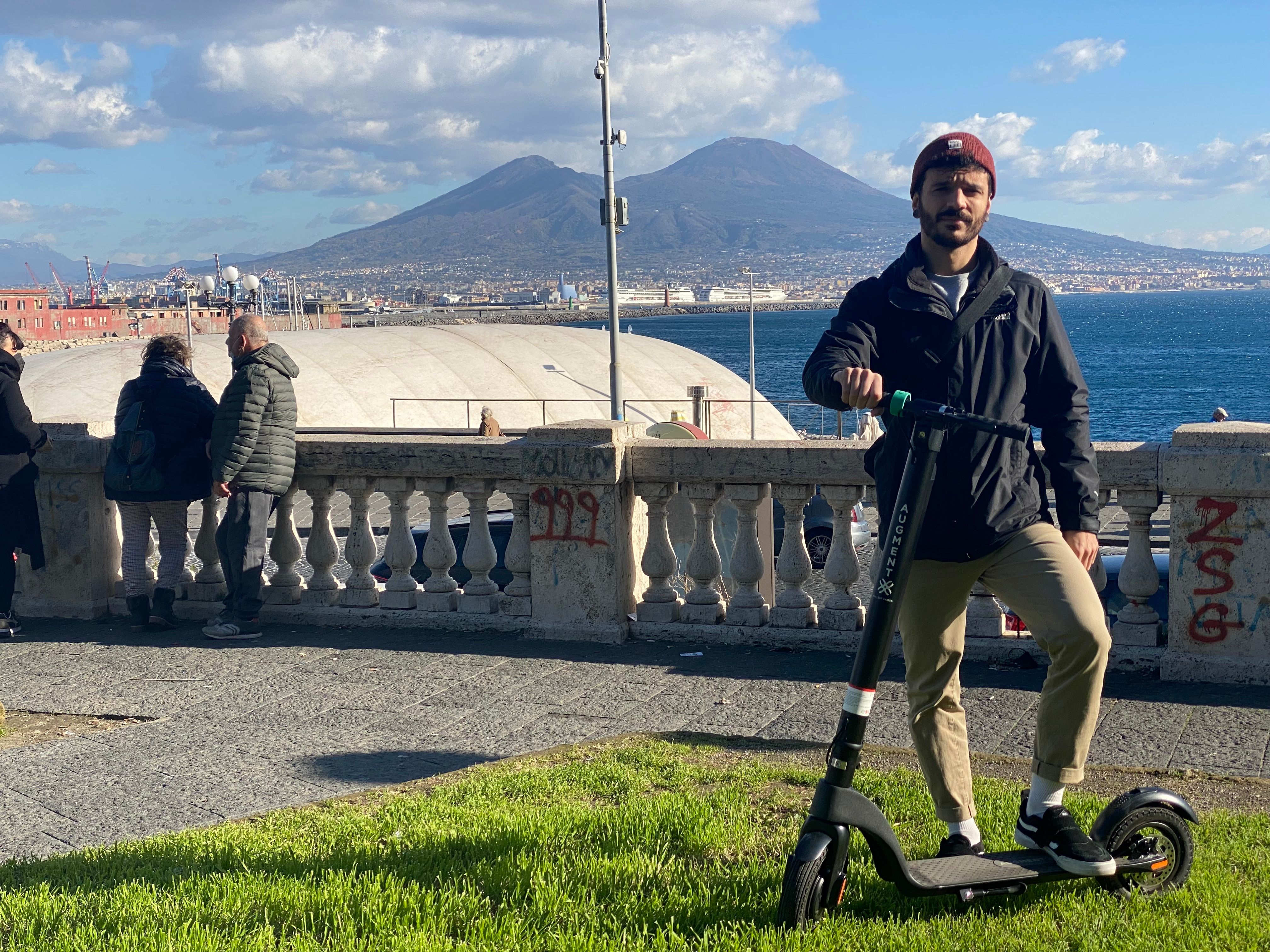 A man standing with an Augment e-scooter on the park