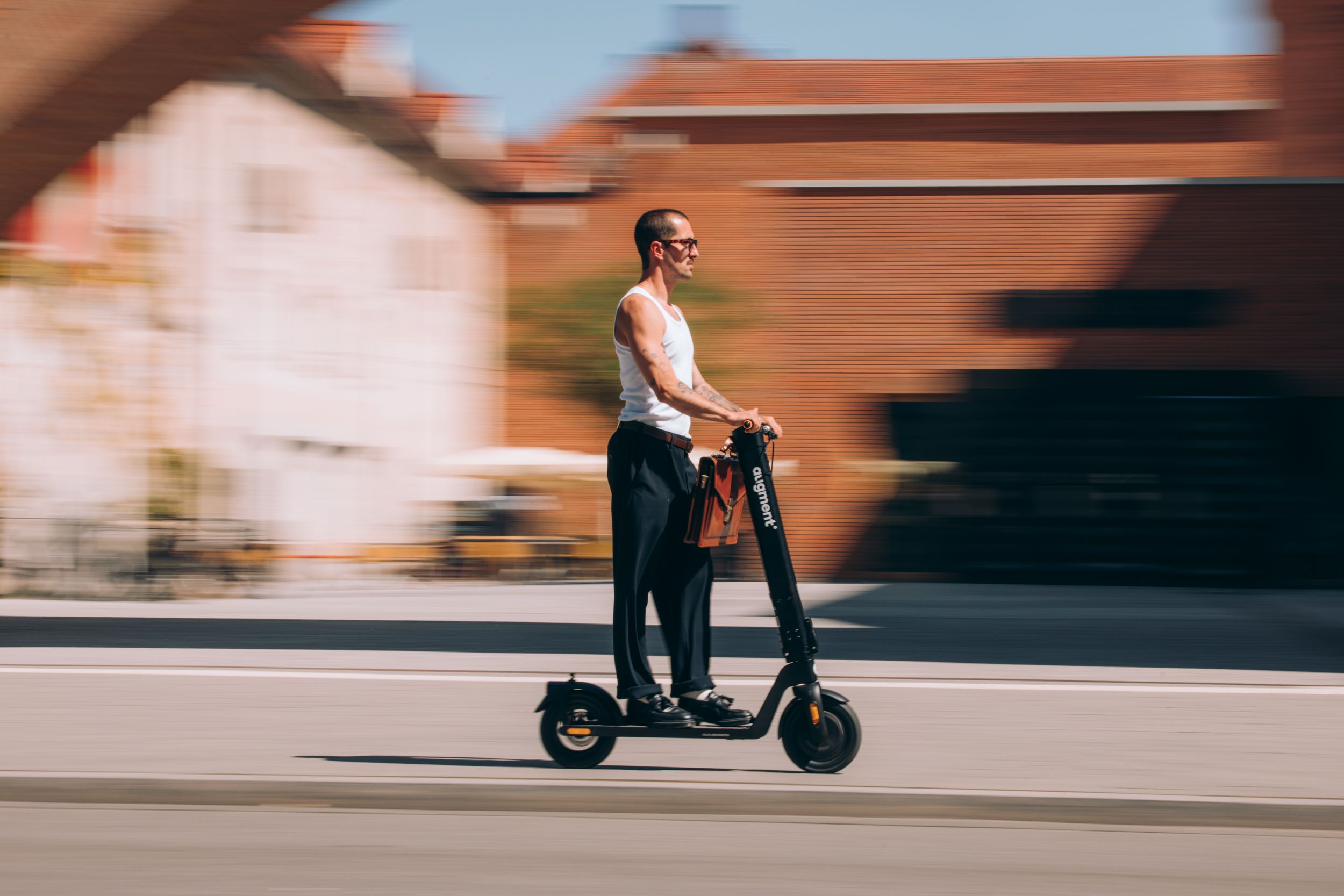 Business man riding Augment e-scooter near a metro station