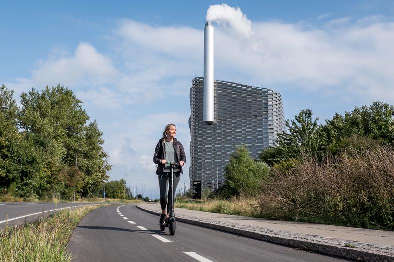 Una donna in sella a un e-scooter Augment sulla pista ciclabile accanto alla natura