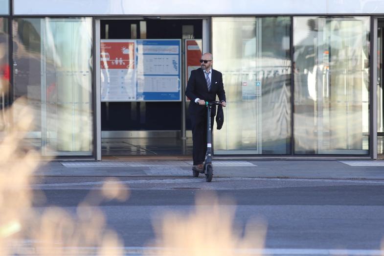 un homme sort du metro en trottinette