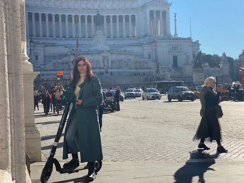 Una donna in piedi con un e-scooter Augment nella piazza della città