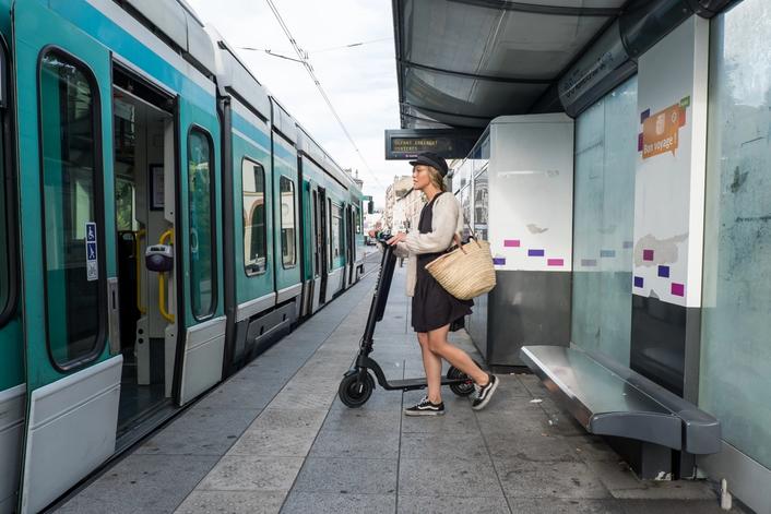 Girl commuting to work by combining train and Augment e-scooter