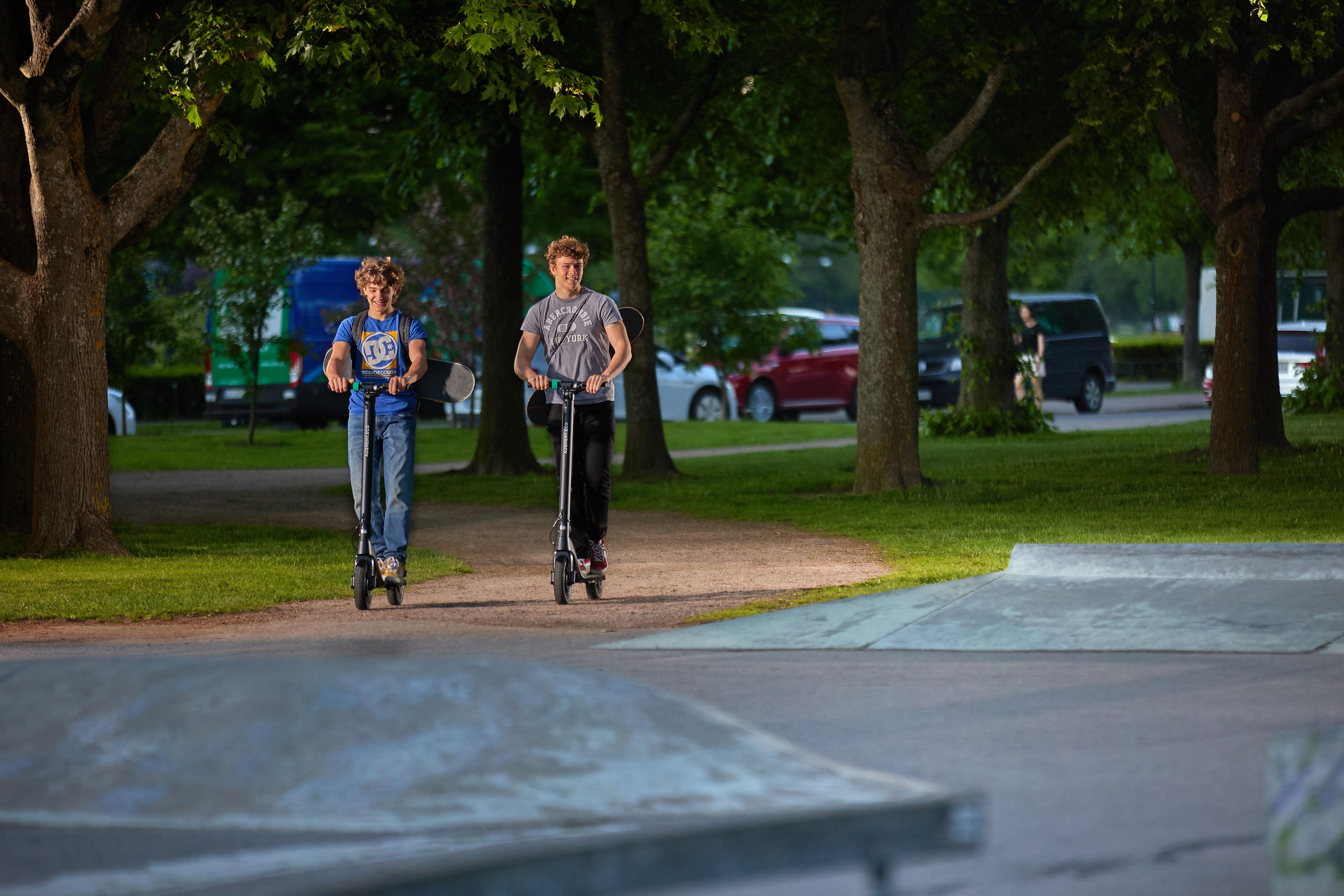 Deux enfants conduisent un scooter électrique Augment dans un parc.