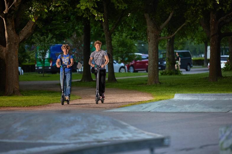Deux enfants conduisent un scooter électrique Augment dans un parc.