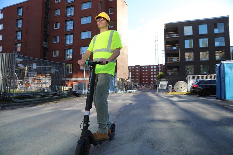 Un employé du batiment roule avec sa trottinette