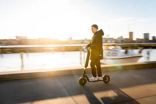 Man riding Augment e-scooter near a harbour