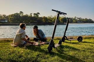 A couple on picnic on a riverside with e-scooters