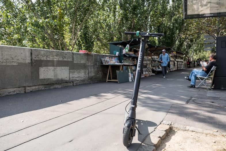 En Augment e-scooter set forfra på gaden ved siden af naturen