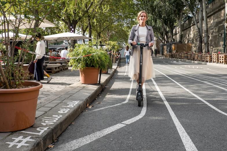 Une femme circulant avec un scooter électrique Augment dans une bande cyclable d'une ville.