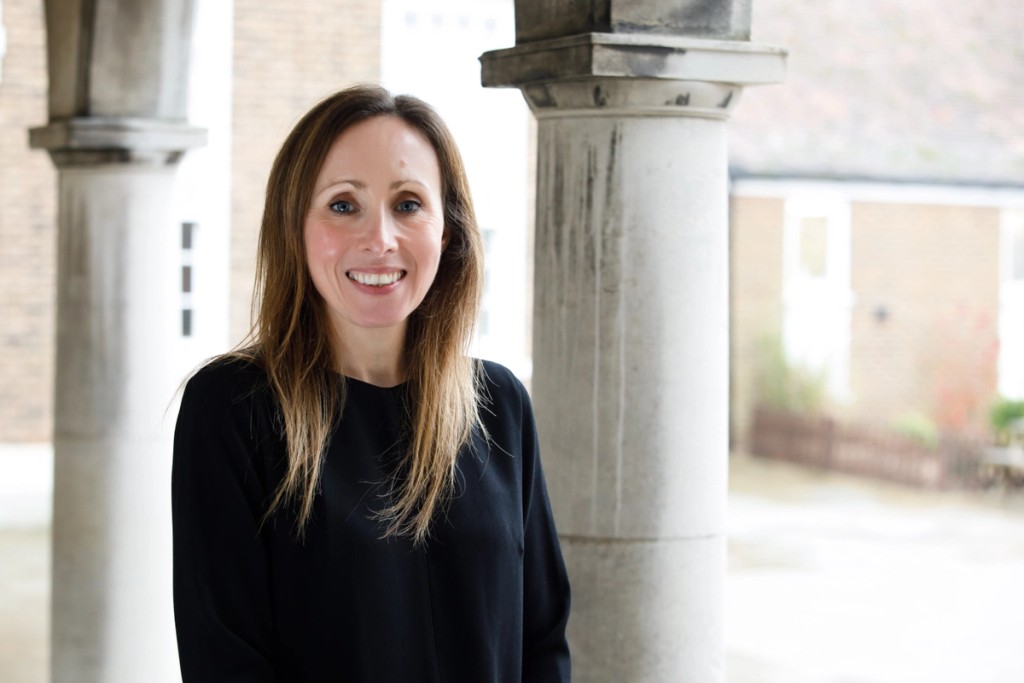 Portrait of Miss Rachel Sutherns, Head of Lower School and Deputy Designated Safeguarding Lead at Mill Hill School, smiling outdoors, wearing a white blazer over a patterned top with a natural green background.