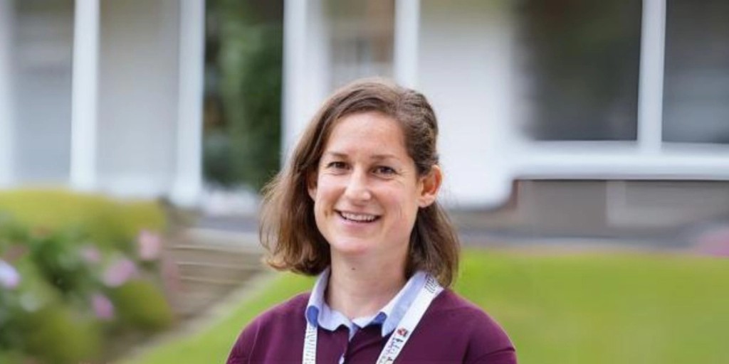 Portrait of Ms. Kaarin Scanlan, Senior Deputy Head (Pastoral) at Mill Hill School, smiling outdoors in a professional headshot, wearing a lanyard and a maroon sweater over a light blue shirt.