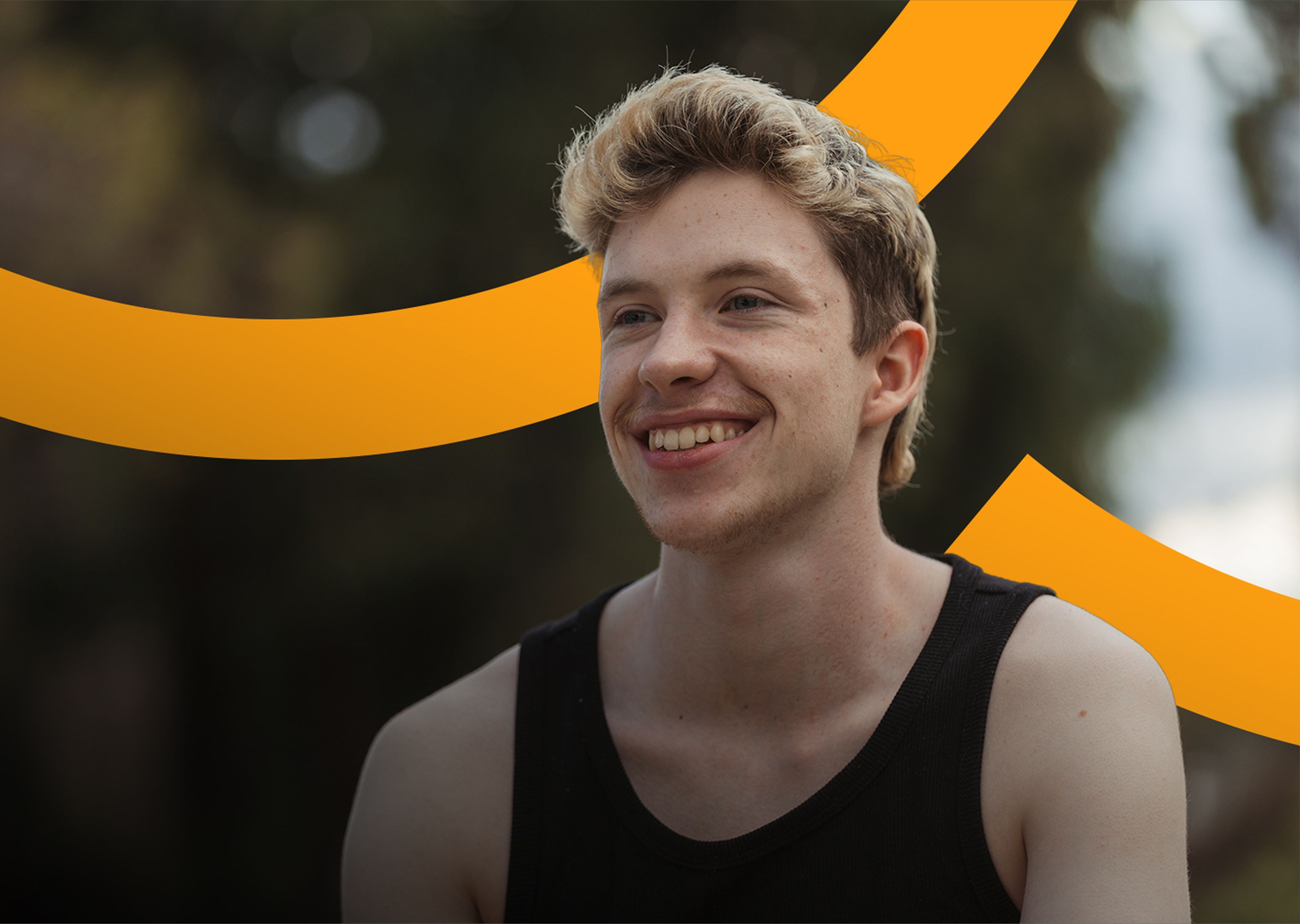 A young individual sitting outside and looking into the distance smiling
