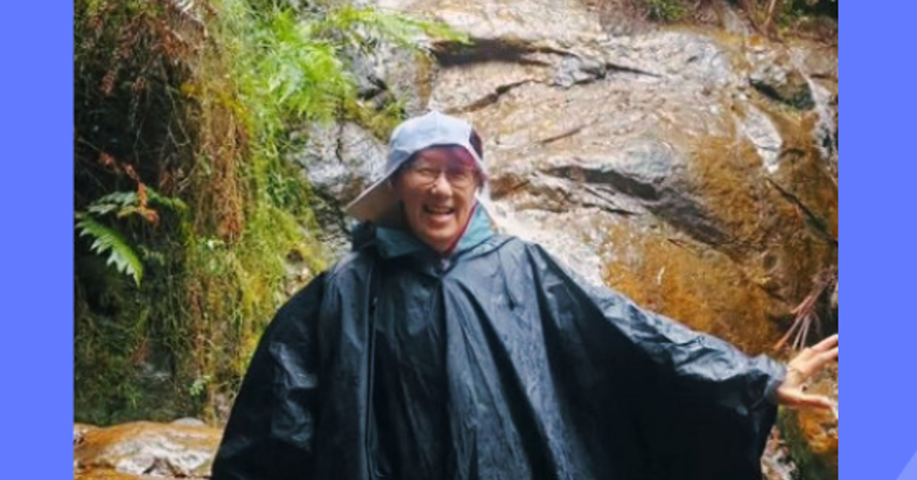 Carer in a jacket, standing in front of a waterfall