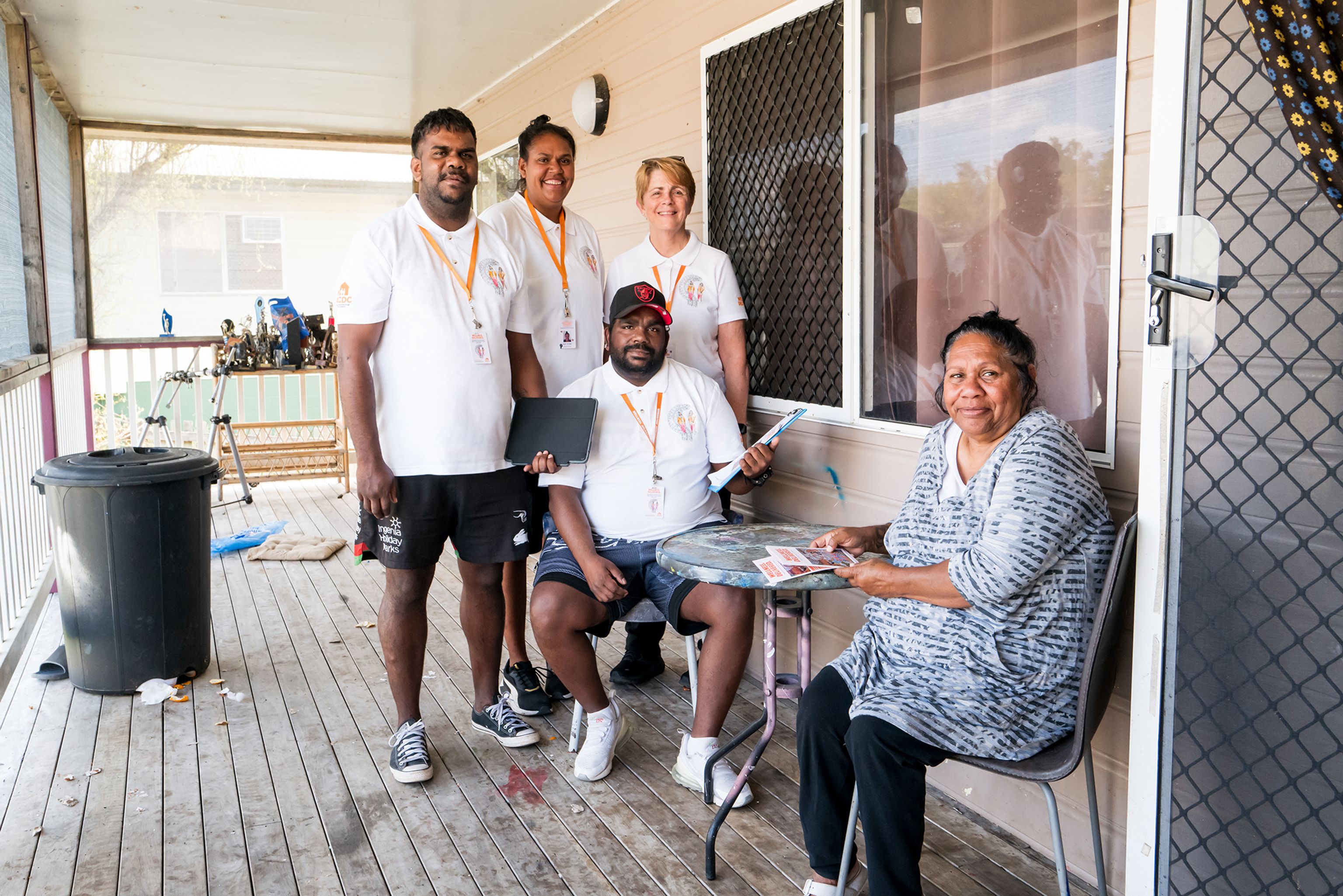 Community Connectors speaking with a woman on the porch of her home