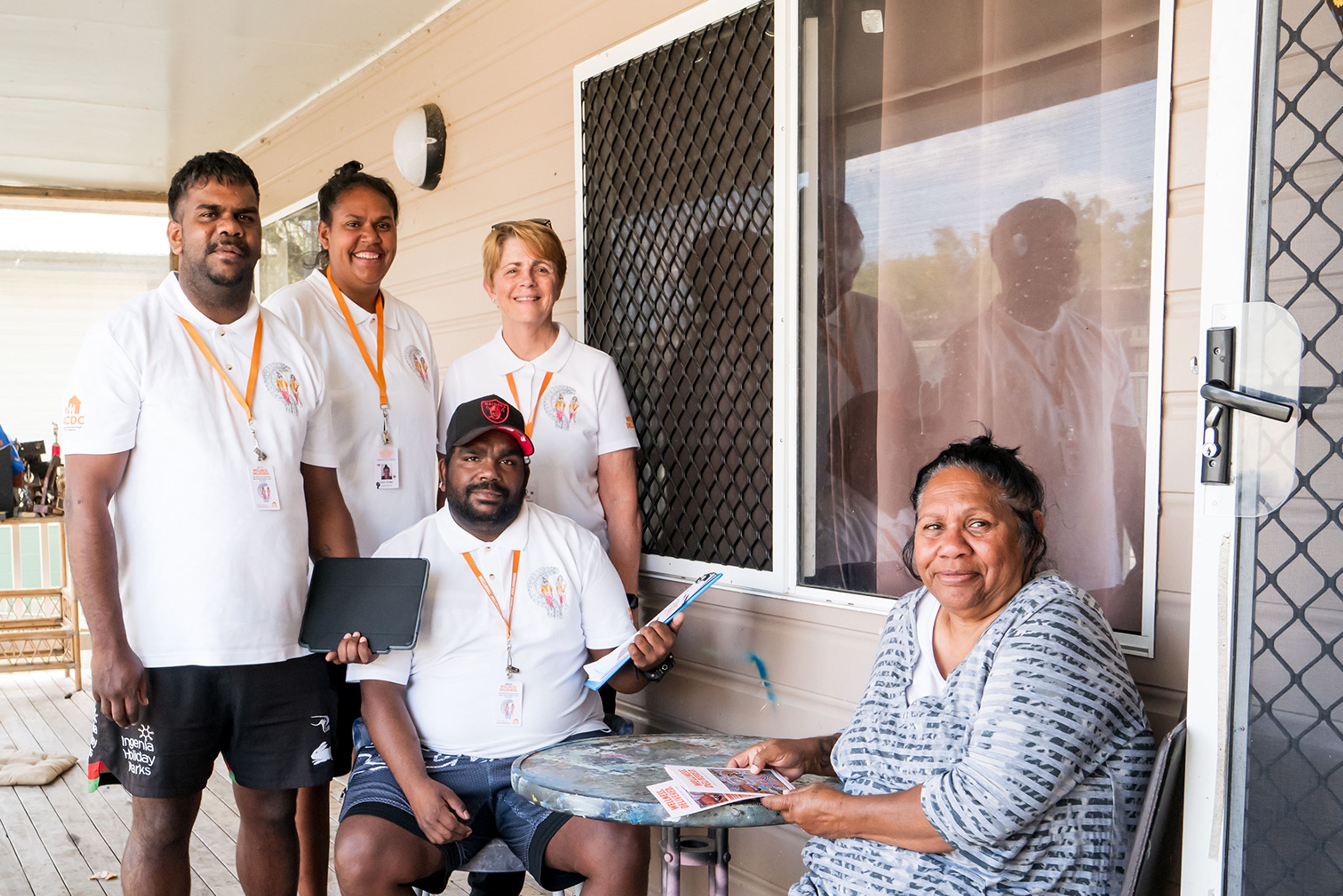 Community Connectors speaking with a woman on the porch of her home