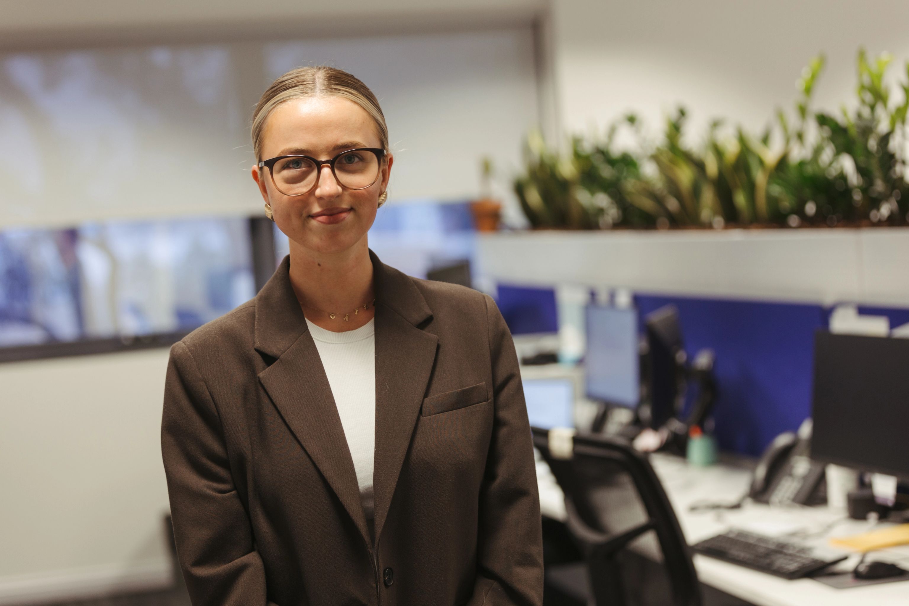 Young female worker standing in an office smiling at camera