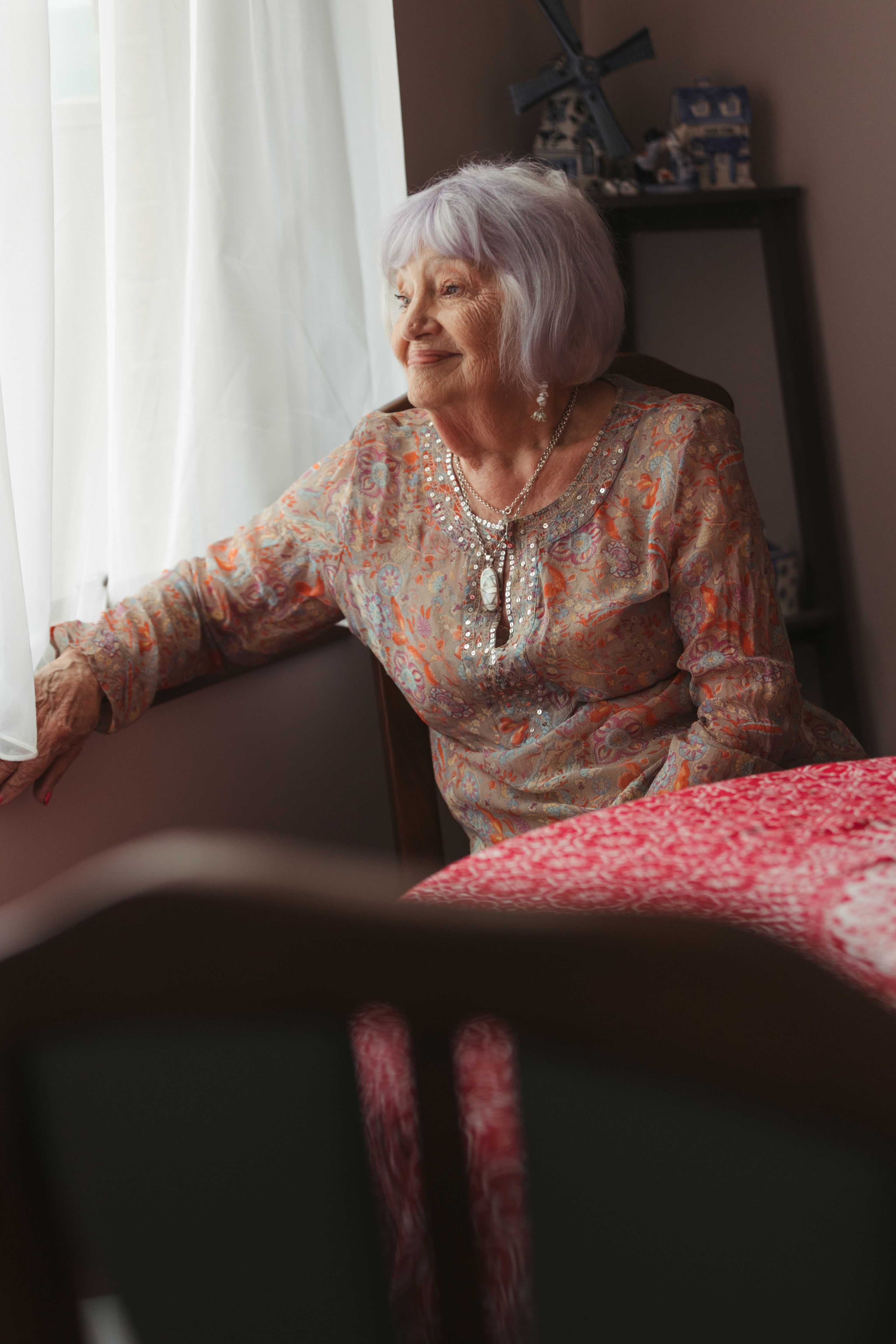 Senior woman sitting at her dining table looking out the window