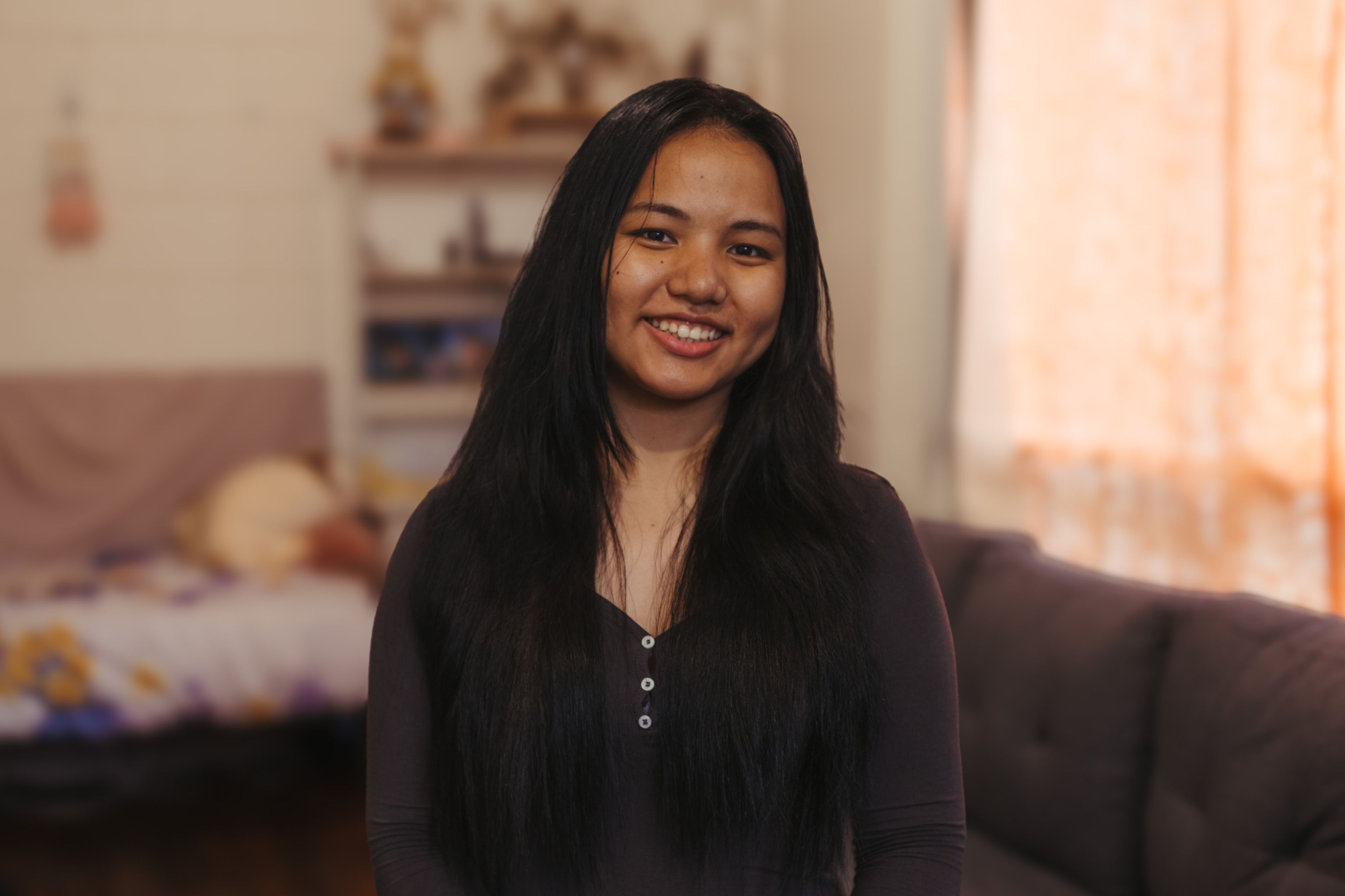 Daughter Daisy in a living room, smiling confidently at the camera.