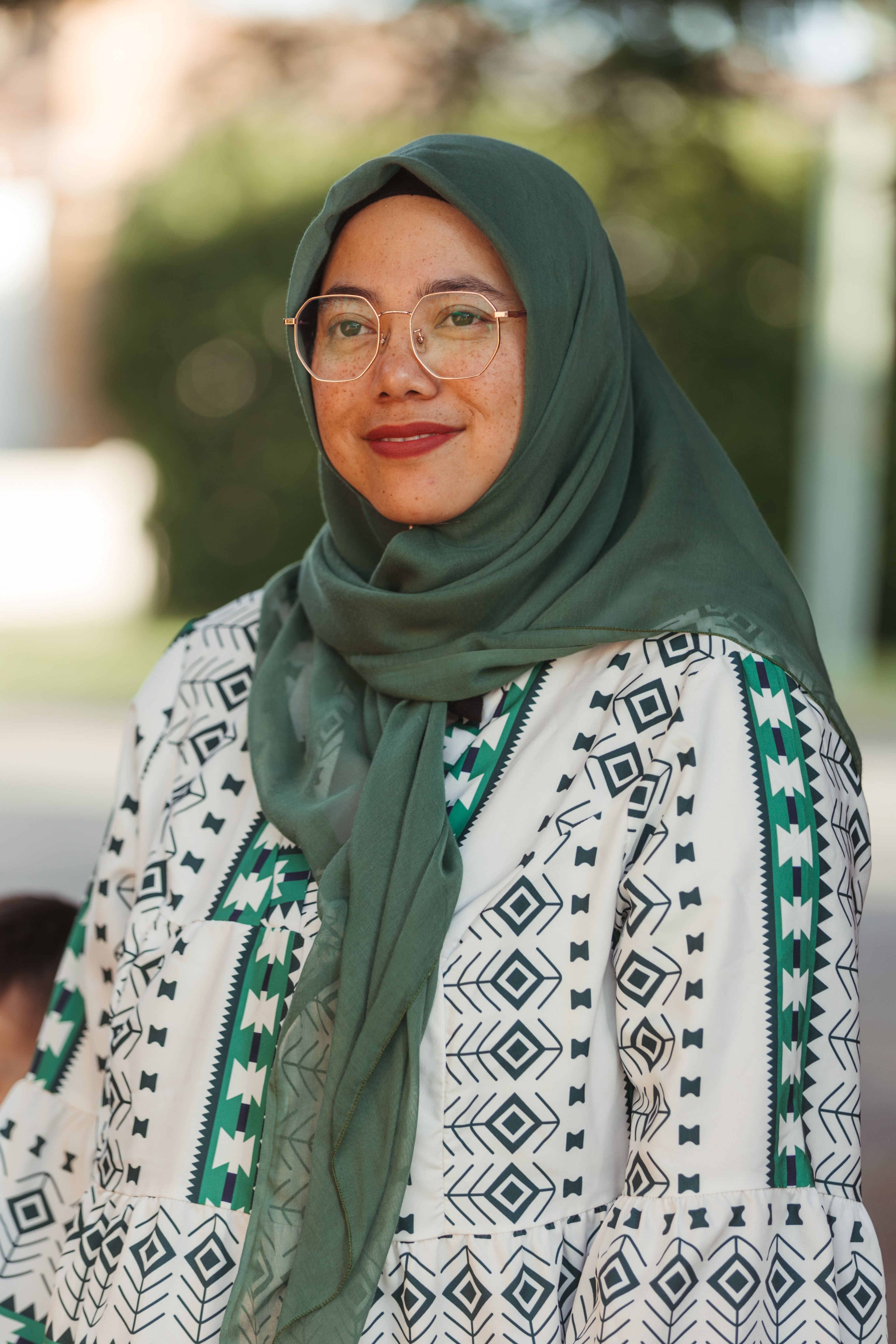 Woman wearing a hijab standing outside and smiling 