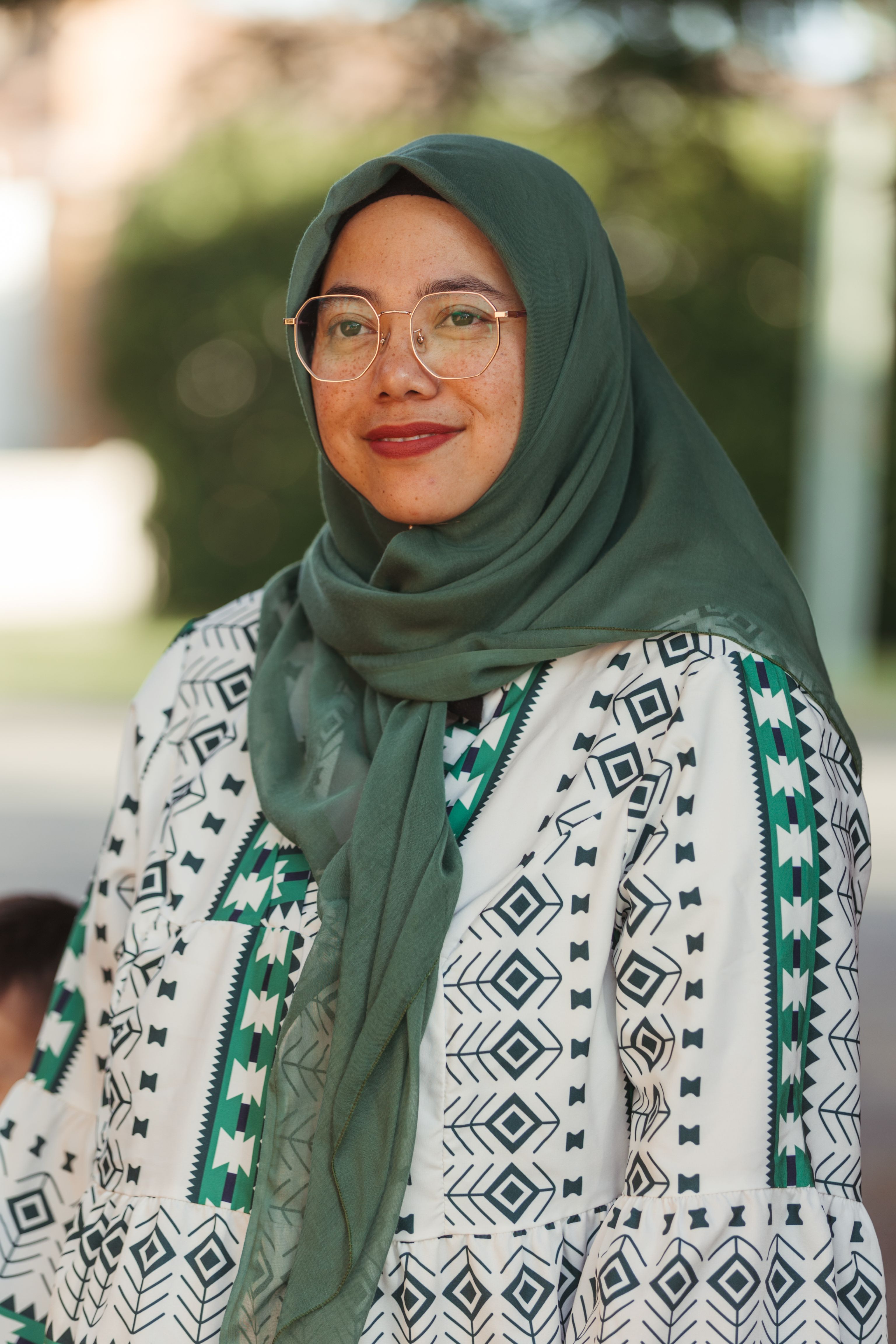 Woman wearing a hijab standing outside and smiling
