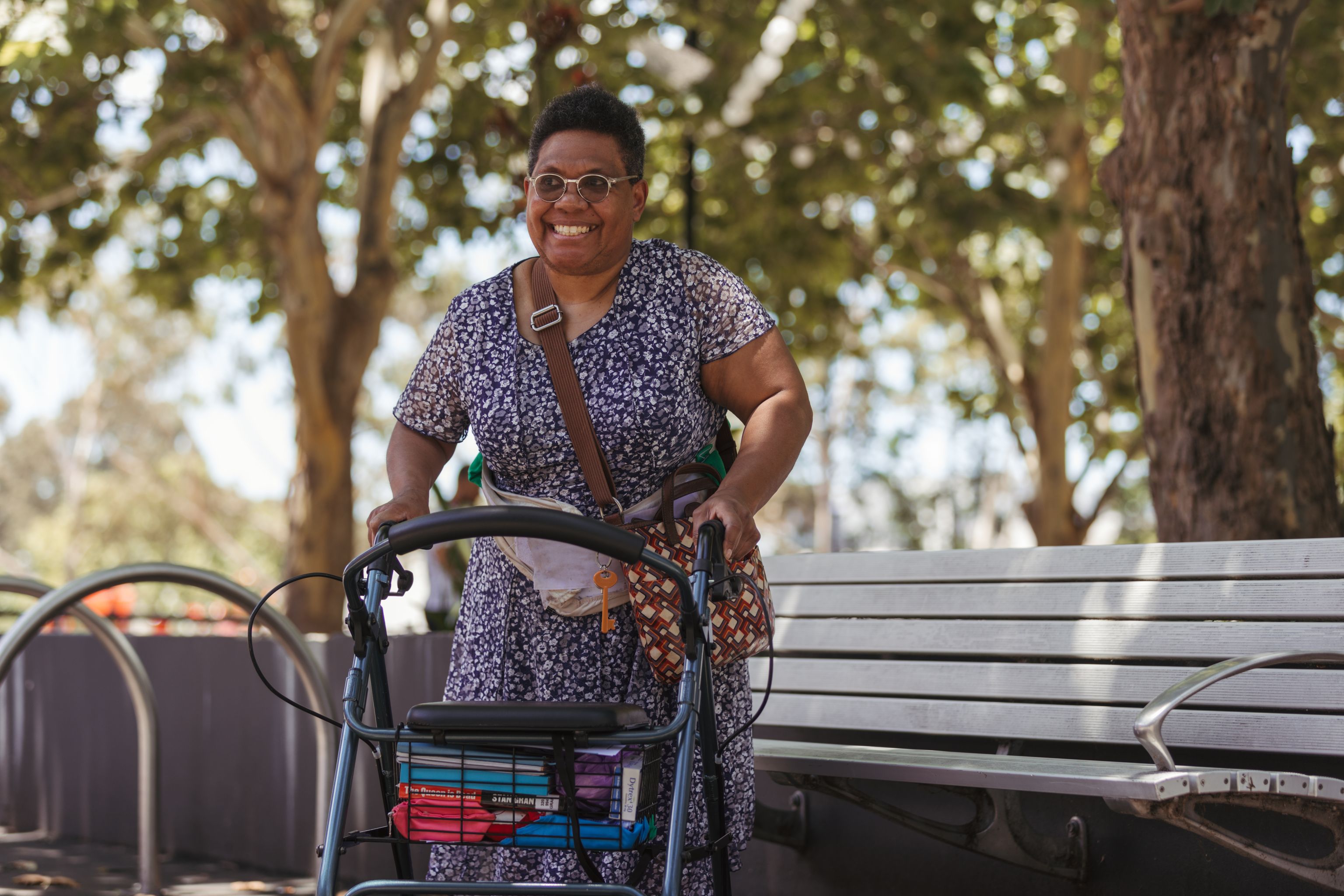Middle aged women standing with a walking frame smiling at camera