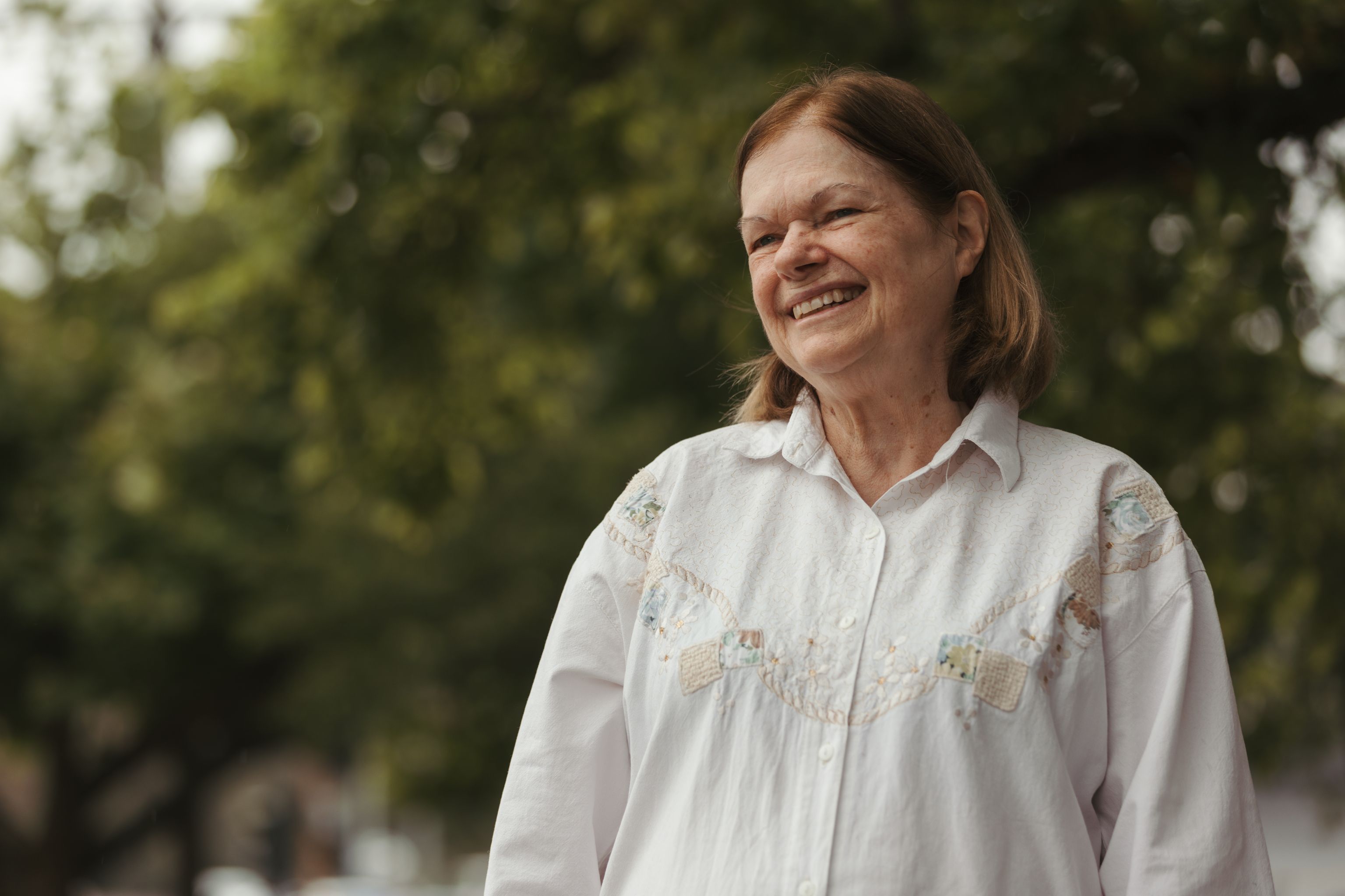 Middle aged Each worker standing outside, looking into the distance and smiling