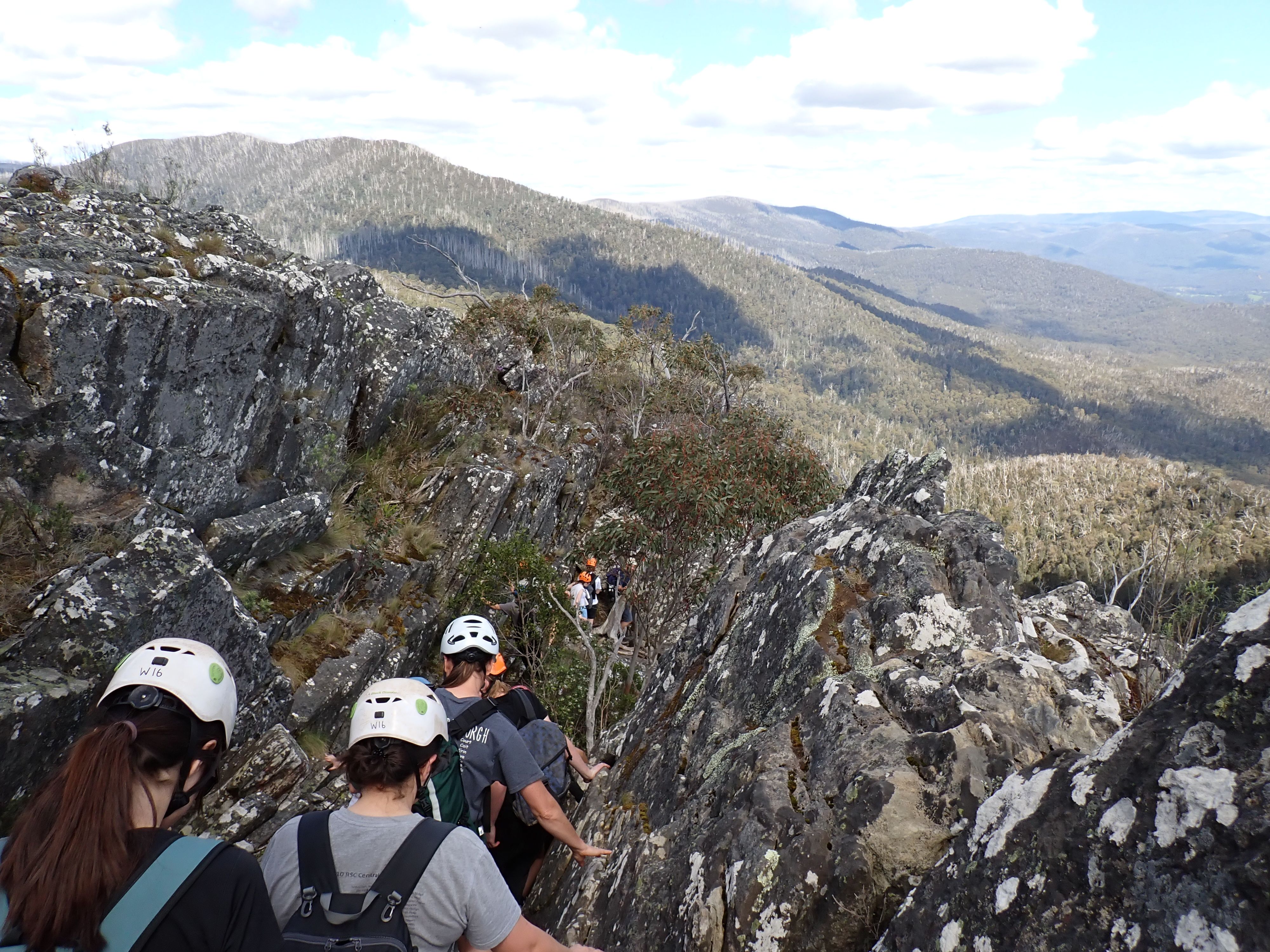 WILD participants navigate a rocky mountain track during an outdoor adventure, surrounded by expansive alpine landscapes.