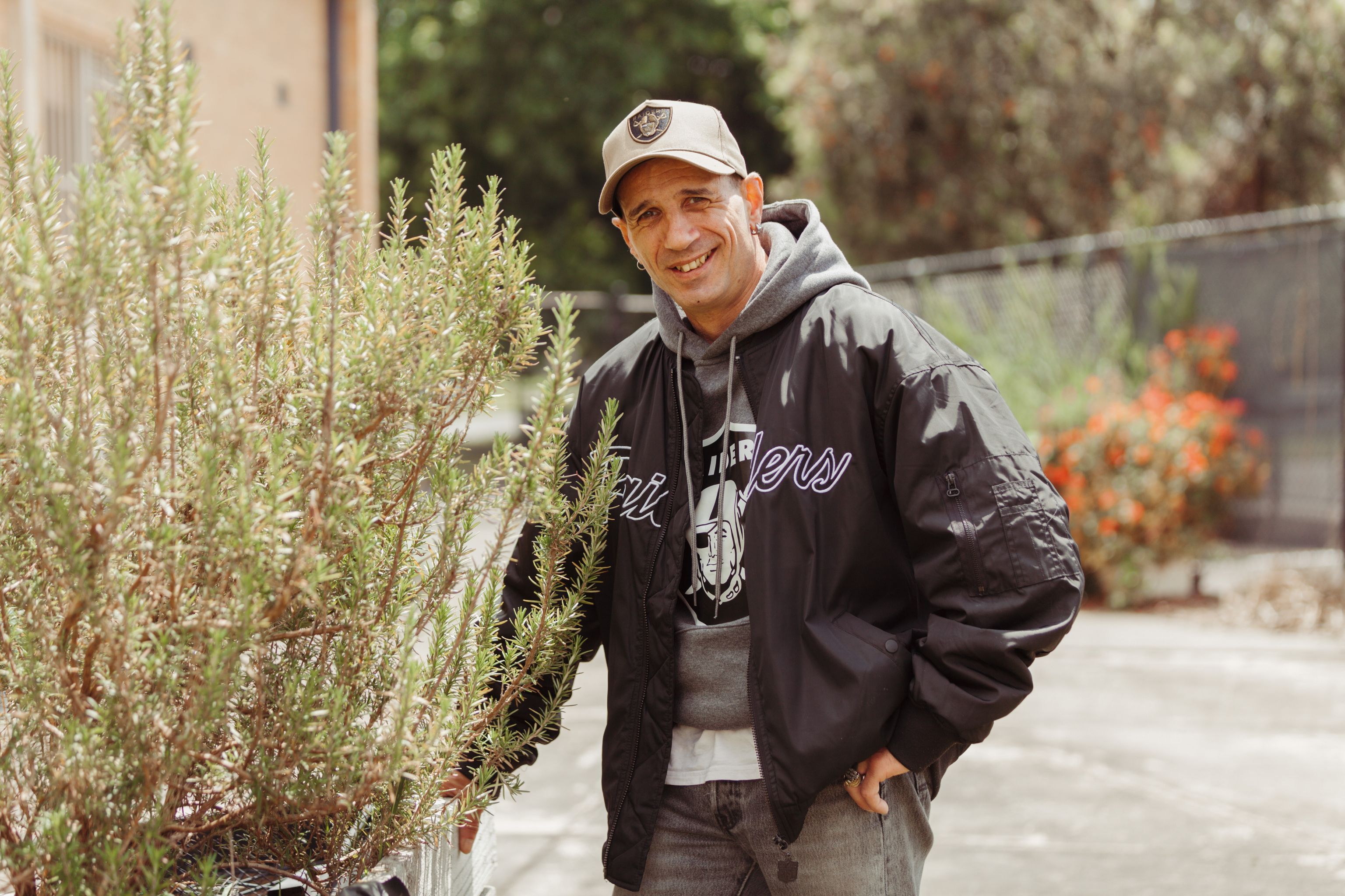 Man standing outside near a plant, smiling